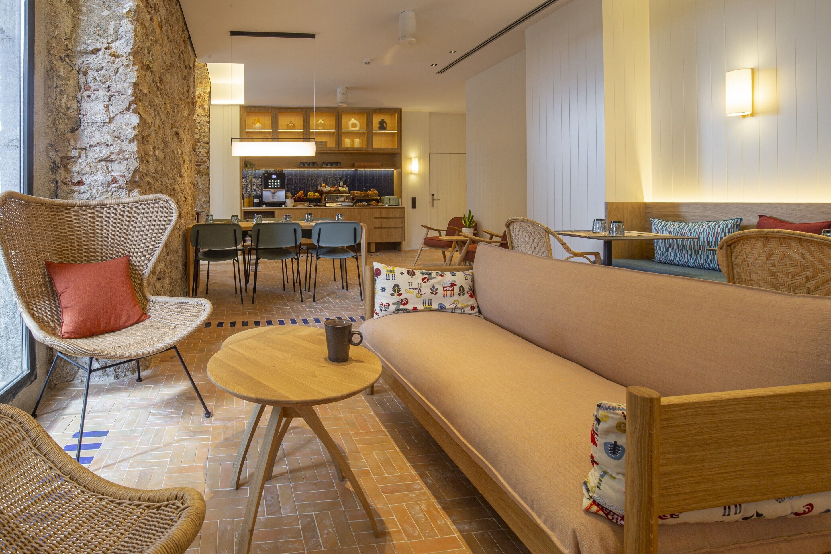 A modern living room with a sofa, chairs, a small table, and a kitchen in the background.
