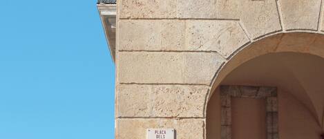 A stone wall with a sign reading "Placa dels Carros" and an arched doorway.