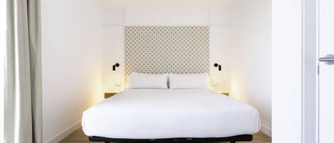 Una habitación de hotel moderna con una cama grande, un cabecero estampado y lámparas de noche.