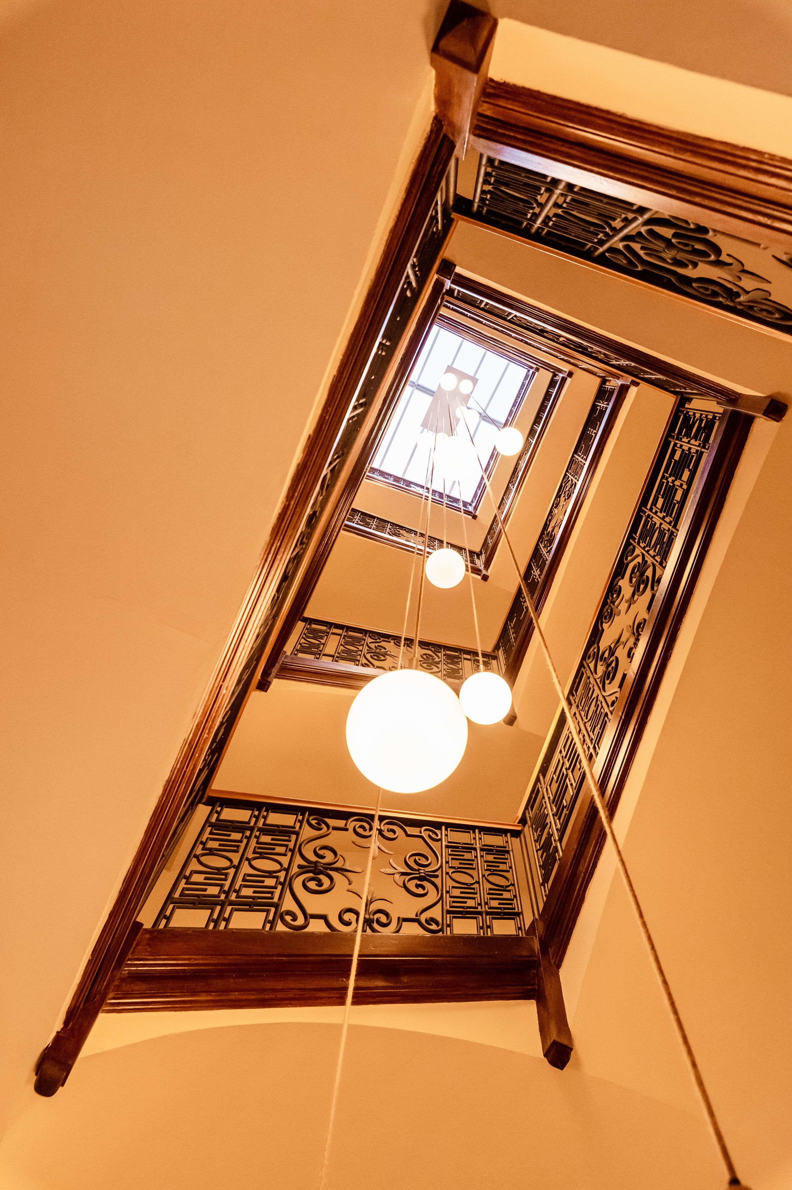 Blick von einer hohen Etage auf eine Treppe mit aufwendiger Metallgalerie und einem Oberlicht.