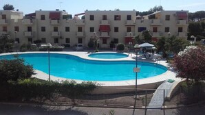 A swimming pool surrounded by a residential building with balconies. - Casa Cernia (Alghero)