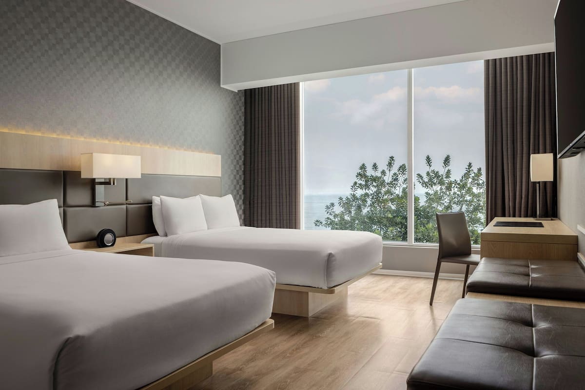 Une chambre d’hôtel moderne avec deux lits, un bureau et une vue sur la ville.