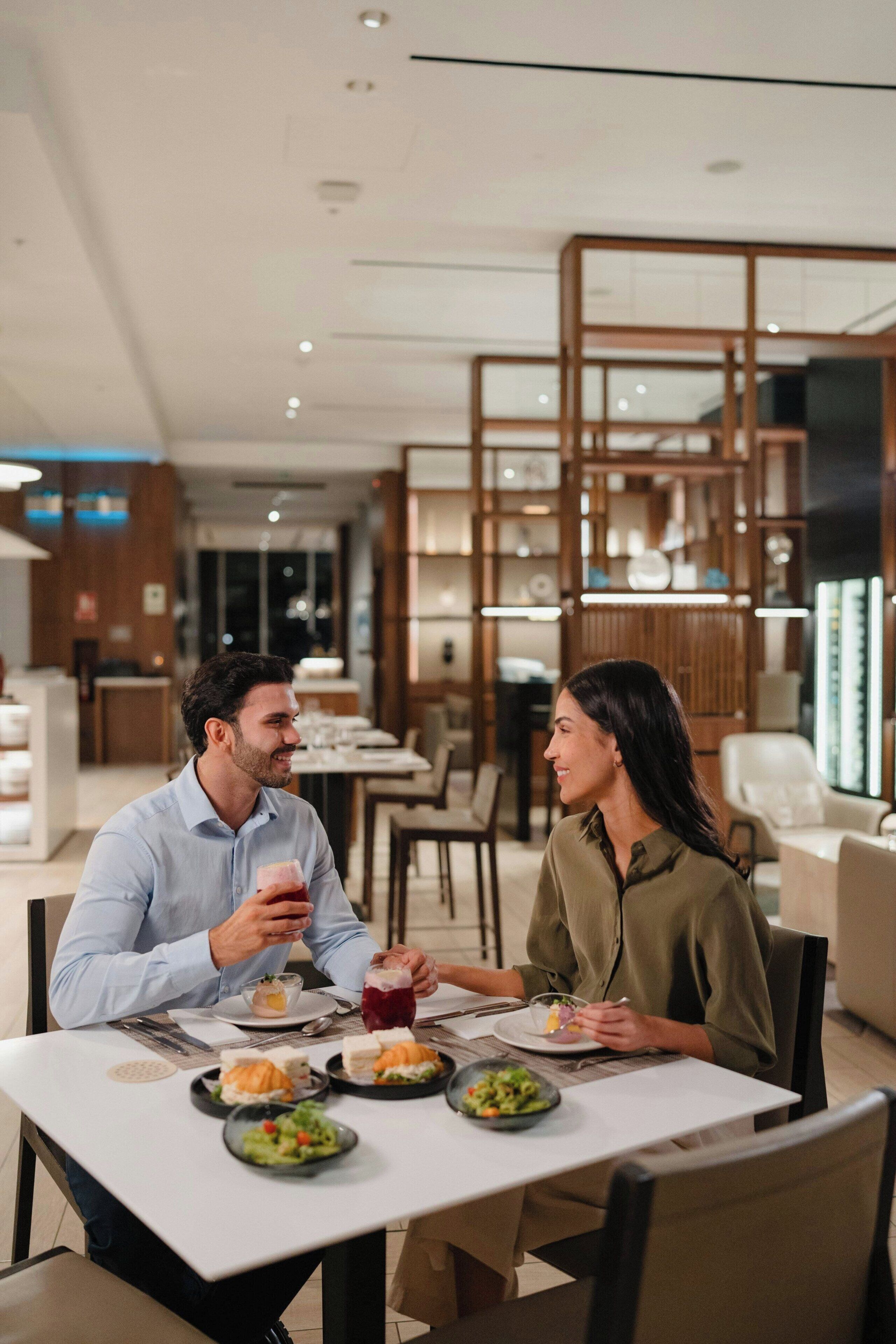 Un espace repas moderne avec une table dressée pour deux personnes, entouré de cloisons en bois et offrant une vue sur l’intérieur du restaurant.