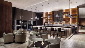 Un espacio moderno de bar con taburetes altos, barra y luz ambiental.