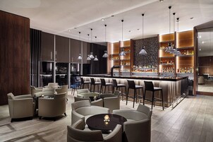 A modern bar area with high stools, a bar counter, and ambient lighting.