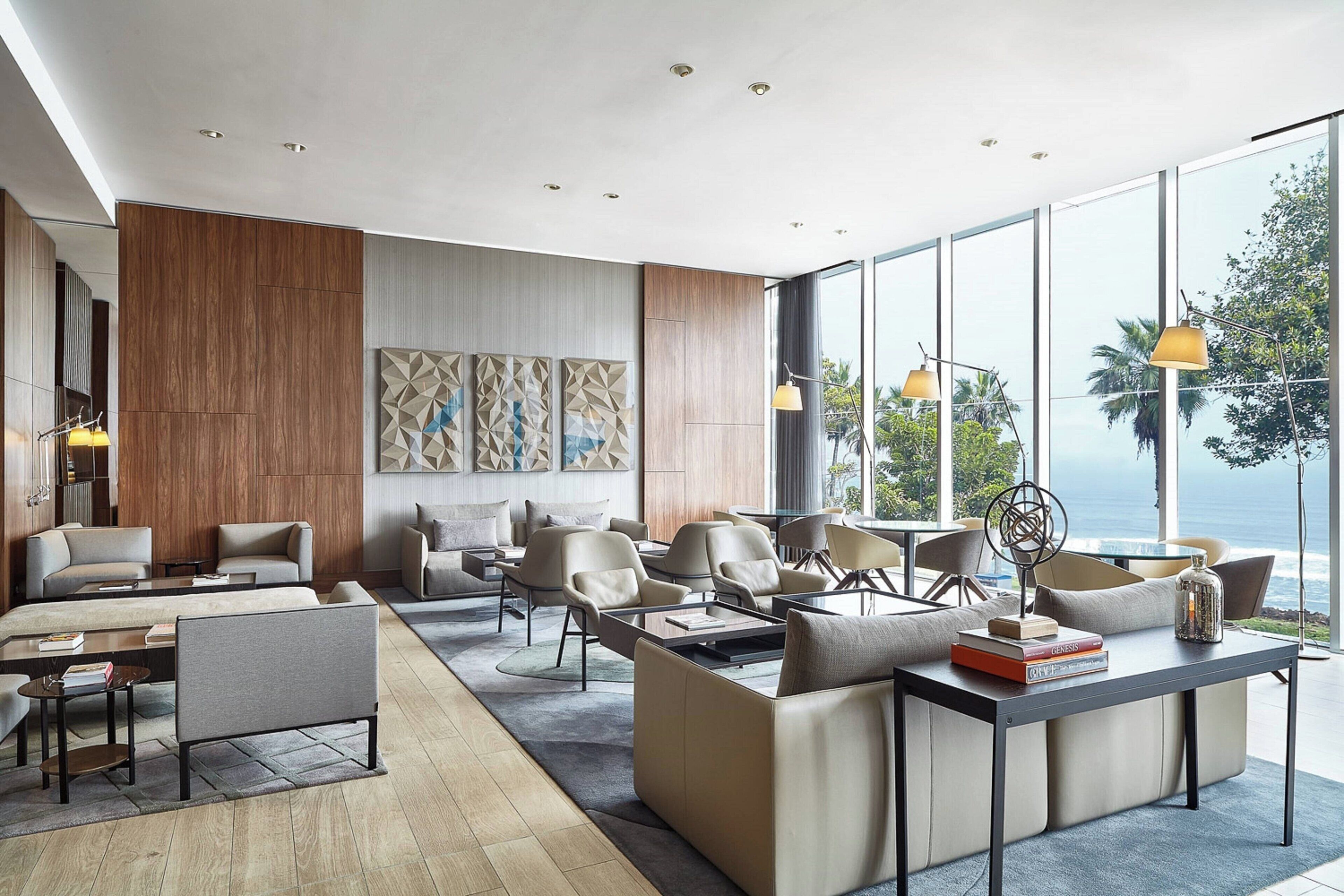 Un lobby moderno de hotel con un amplio espacio para sentarse, una mesa de centro y vista al océano.