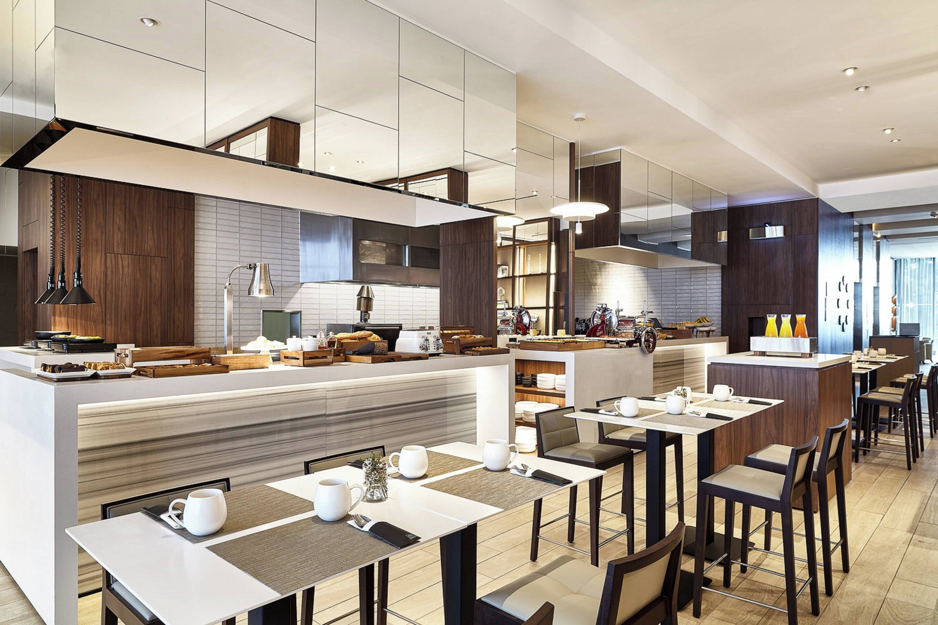 A modern restaurant with a long counter, multiple tables, and a variety of seating options.