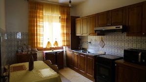Una cocina con armarios de madera, una estufa negra, un fregadero y una mesa de comedor con mantel amarillo.