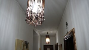 Un pasillo con una lámpara geométrica original, una puerta de madera y arte abstracto en la pared.