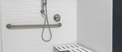 Une douche équipée d’un pommeau de douche à main, d’un robinet à main et d’un panneau de commande fixé au mur.