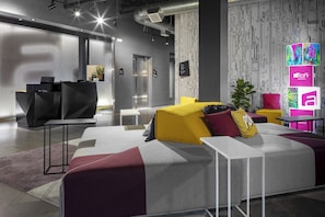 Un hall d’hôtel moderne avec un canapé d’angle, un comptoir d’accueil et un mur orné d’un motif.