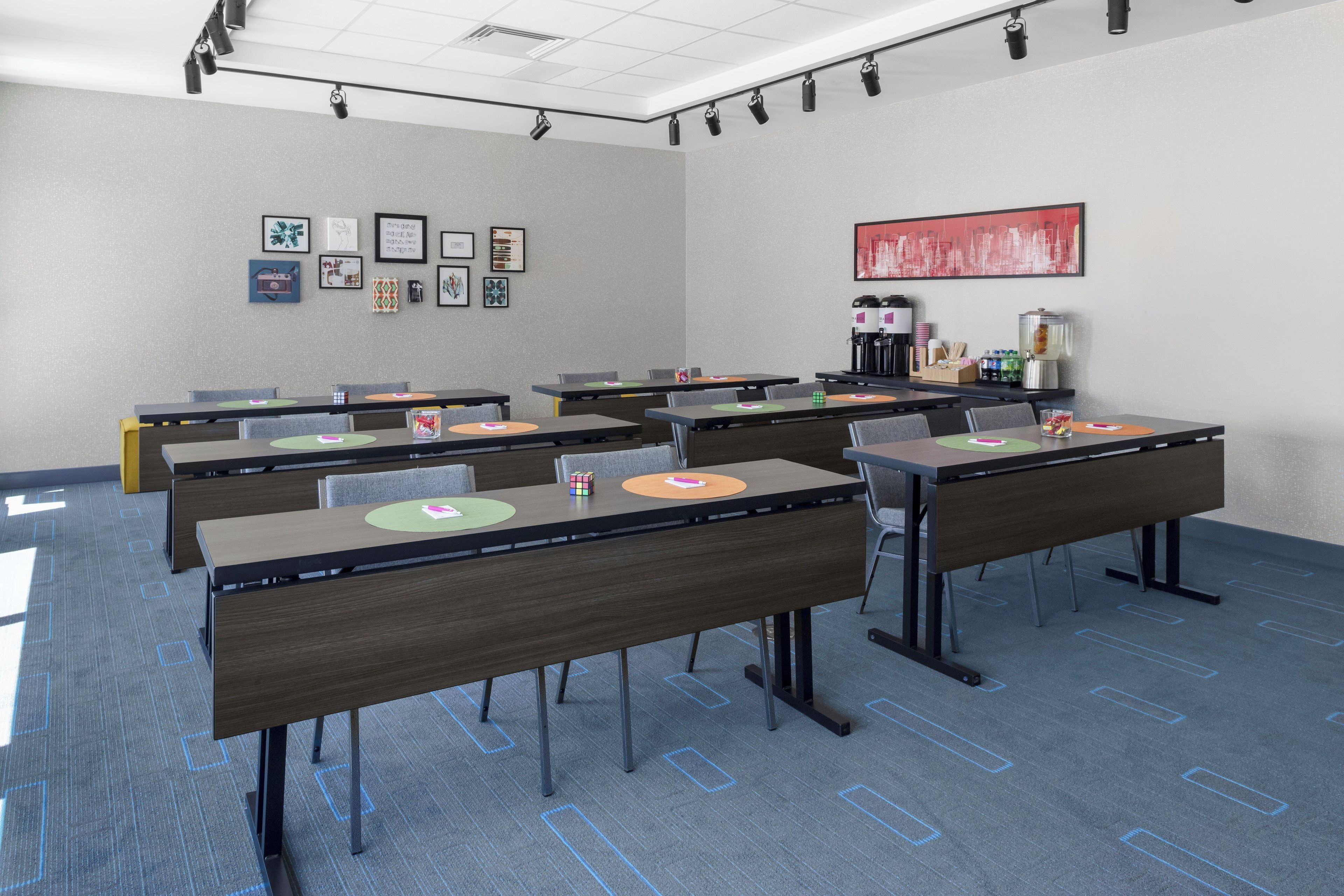 Een vergaderruimte met tafels, stoelen, een koffiehoek en kunstwerken in lijsten aan de muren.