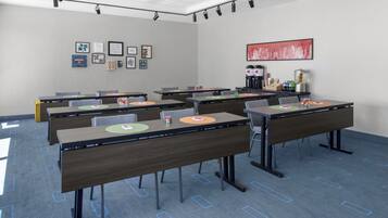 Een vergaderruimte met tafels, stoelen, een koffiehoek en kunstwerken in lijsten aan de muren.