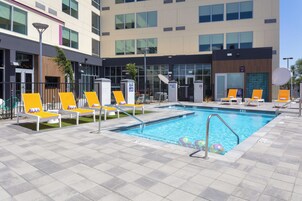 Una piscina con múltiples tumbonas y una zona junto a la piscina.