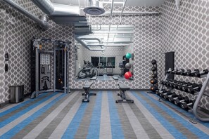 A gym with exercise equipment, a mirror, and a patterned wall.