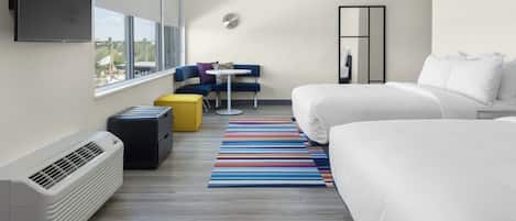 A modern hotel room with a large bed, a sofa, a small table, and a TV mounted on the wall.