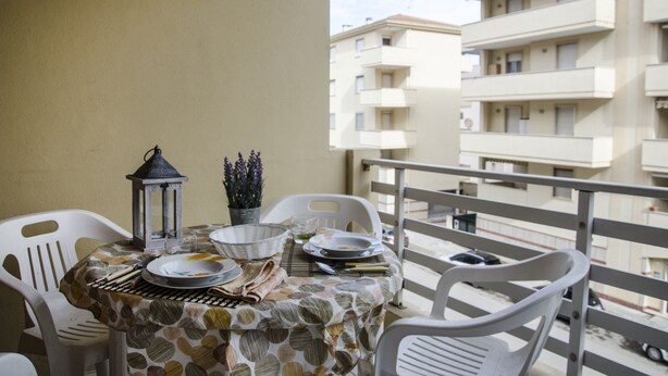 A balcony table with chairs, a lantern, and a potted plant. - Casa Mostella (Alghero)