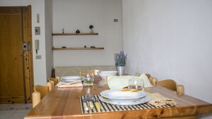 A dining table set with plates, glasses, and cutlery, surrounded by wooden chairs. - Casa Mostella (Alghero)