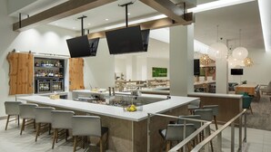 Una cocina moderna con una isla central, asientos tipo bar y una zona de bar con estantes llenos de botellas.