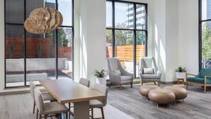 Un interior moderno con ventanas amplias, una mesa de comedor de madera, sillas grises y una lámpara original de fibras tejidas.