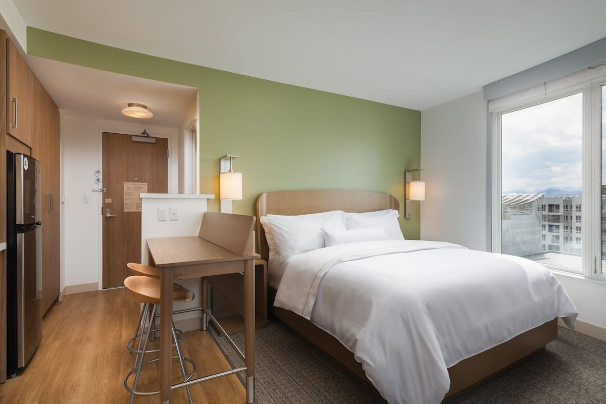 A hotel room with a bed, a desk, and a kitchenette.
