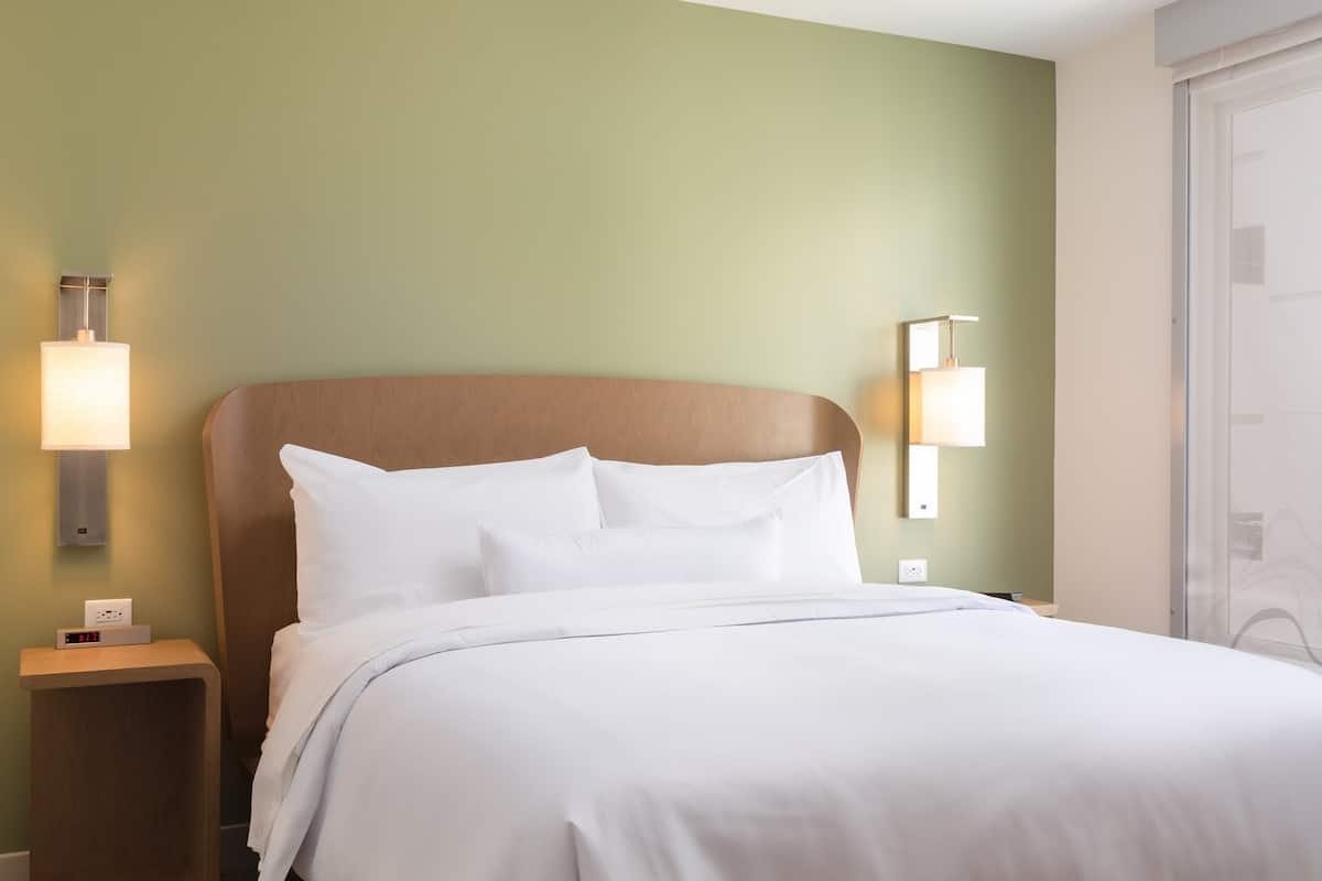 A neatly made bed with white linens in a hotel room.