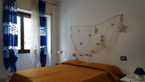 Een slaapkamer met een bed, nachtkastje, lamp en een decoratieve wandversiering.