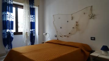 Um quarto com uma cama, uma mesa de cabeceira, uma luminária e um objeto decorativo na parede.