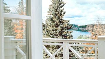 Enjoy a serene view of the surrounding landscape from this deck with a body of water and trees in the distance.