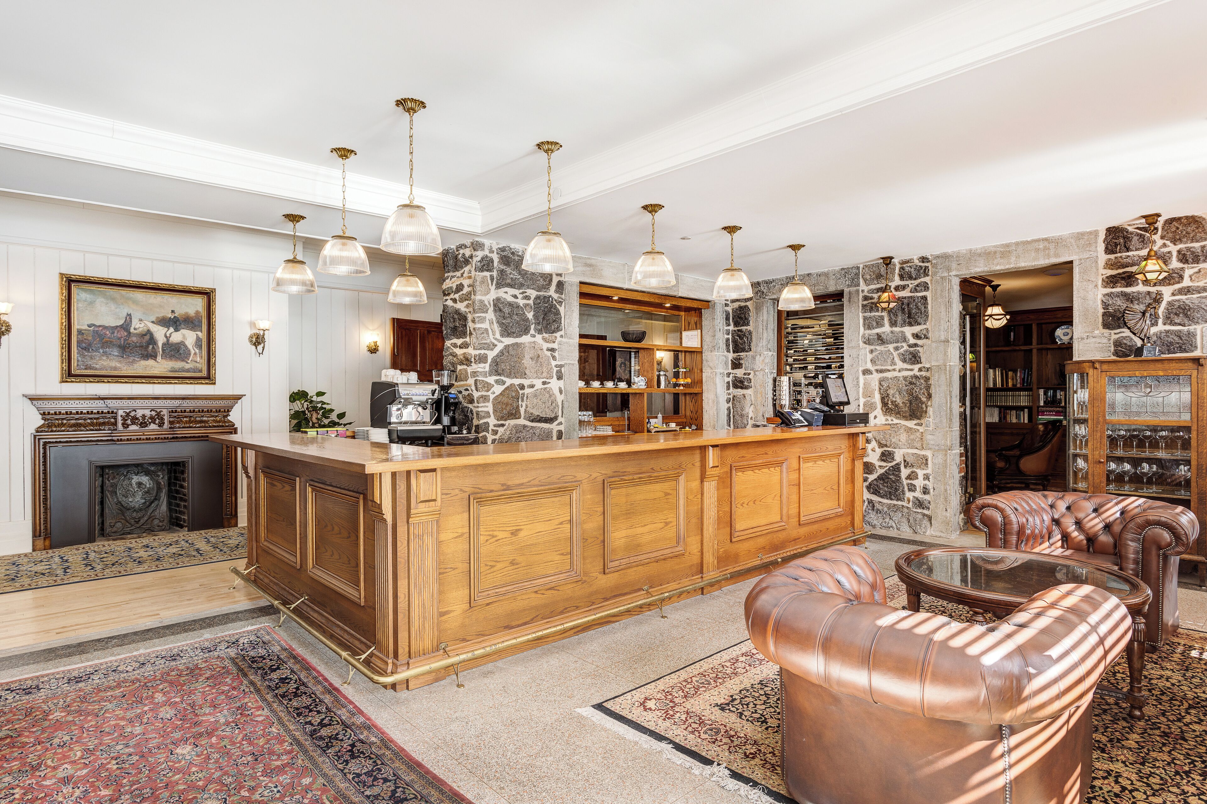 A spacious living area with a wooden bar, leather furniture, stone walls, and hanging pendant lights.
