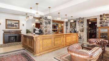 A spacious living area with a wooden bar, leather furniture, stone walls, and hanging pendant lights.