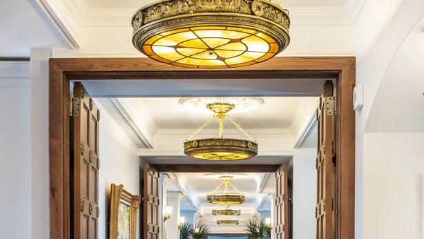 A hallway with a patterned carpet, wooden doors, and a chandelier. - StoneHaven Le Manoir Relais & Châteaux (Sainte-Agathe-des-Monts)