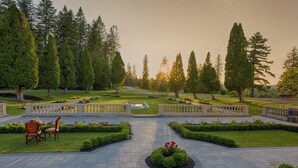 A formal garden with a central pathway, benches, and neatly trimmed hedges. - StoneHaven Le Manoir Relais & Châteaux (Sainte-Agathe-des-Monts)