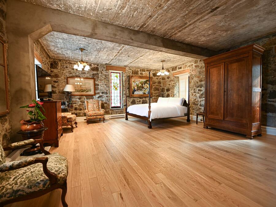Een slaapkamer met een houten bed, stenen muren en een stenen open haard.