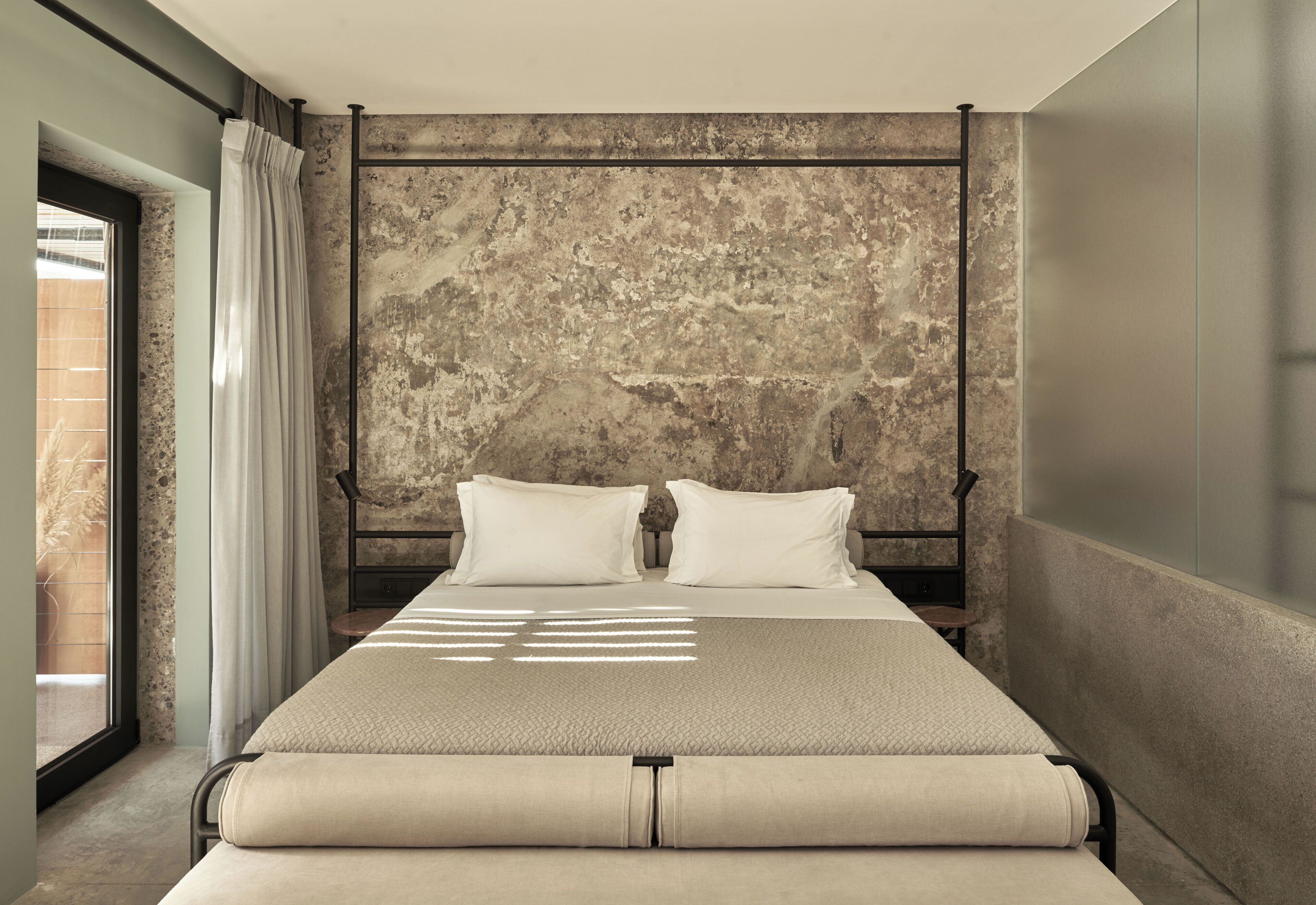 Une chambre moderne avec un grand lit, un mur à texture et une fenêtre avec des rideaux.