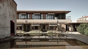 Un edificio moderno con piscina, asientos al aire libre y cielo despejado.