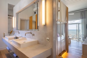 A modern bathroom with two sinks, a large mirror, and a view of the sea through a glass door. - Dexamenes Seaside Hotel (Ilida)