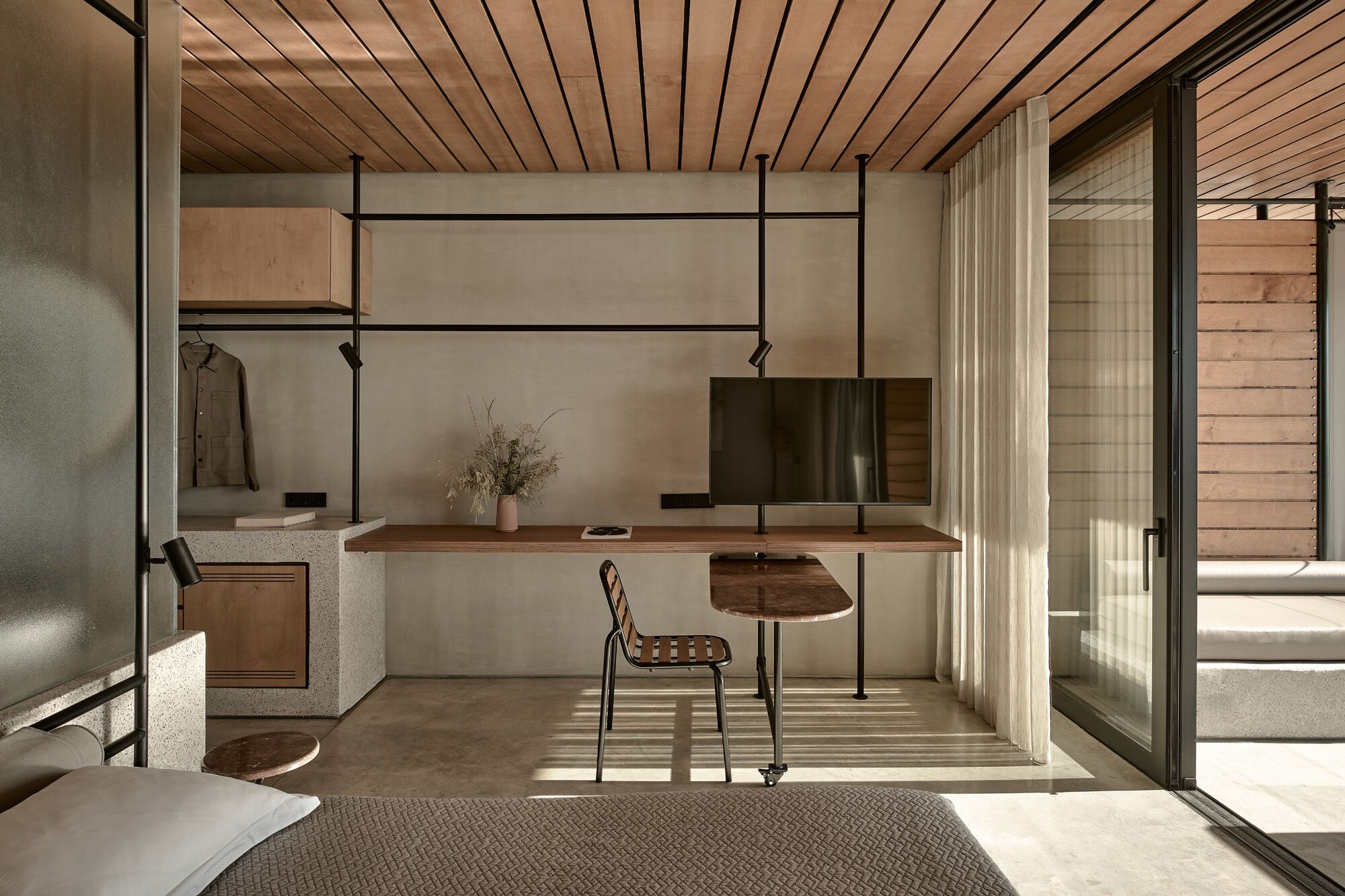 Un interior moderno con techo de madera, televisor de pantalla plana, una mesita y una silla.