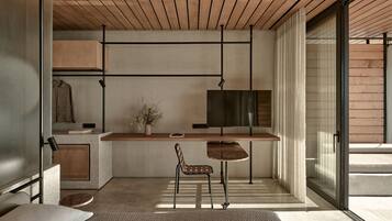 Un interior moderno con techo de madera, televisor de pantalla plana, una mesita y una silla.