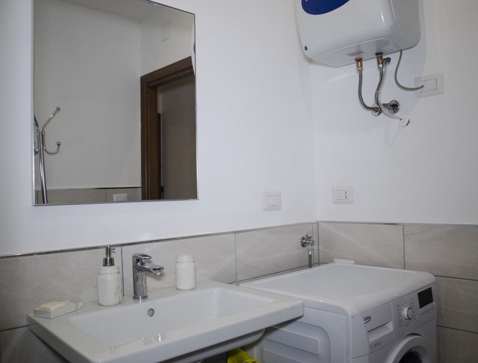 Une salle de bain avec un lavabo, un miroir et un lave-linge.