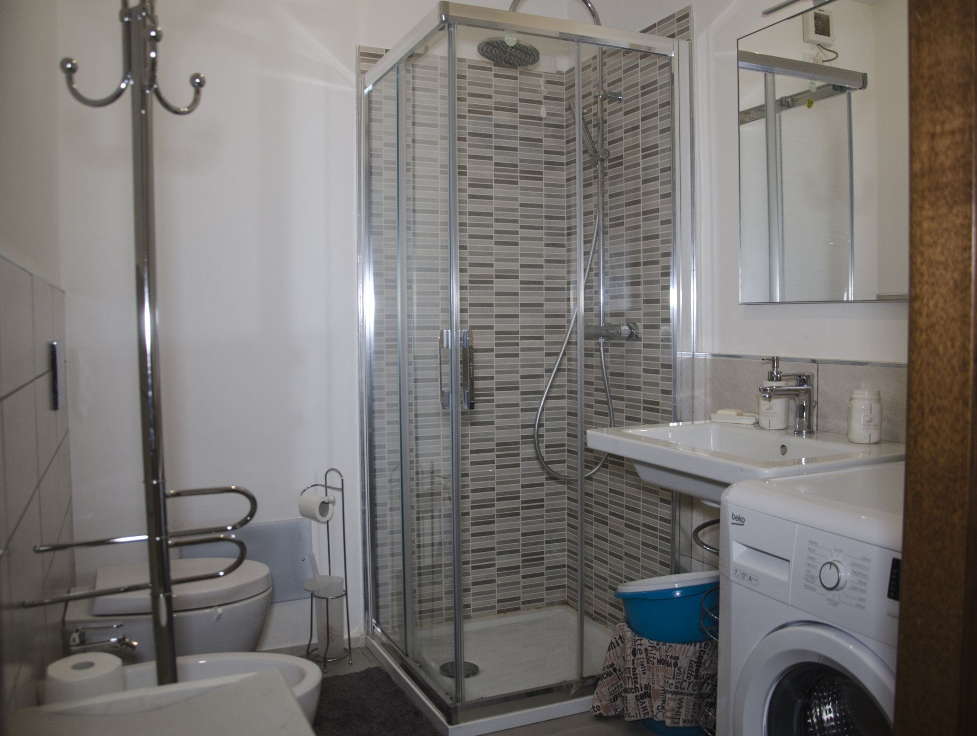 A modern bathroom with a glass-enclosed shower, a toilet, a sink, and a washing machine.