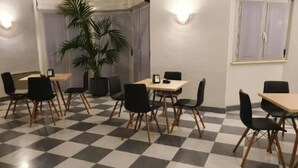 A dining area with checkered flooring, black chairs, and a potted plant. - Hotel Azzano Decimo (Azzano Decimo)