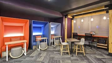 A modern lounge area with seating, tables, and a computer station.