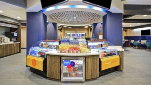Una estación autoservicio de bebidas con una variedad de opciones para beber y picar, una pantalla digital y un refrigerador expositor.