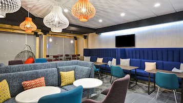A modern lounge area with blue sofas, teal chairs, and white tables.
