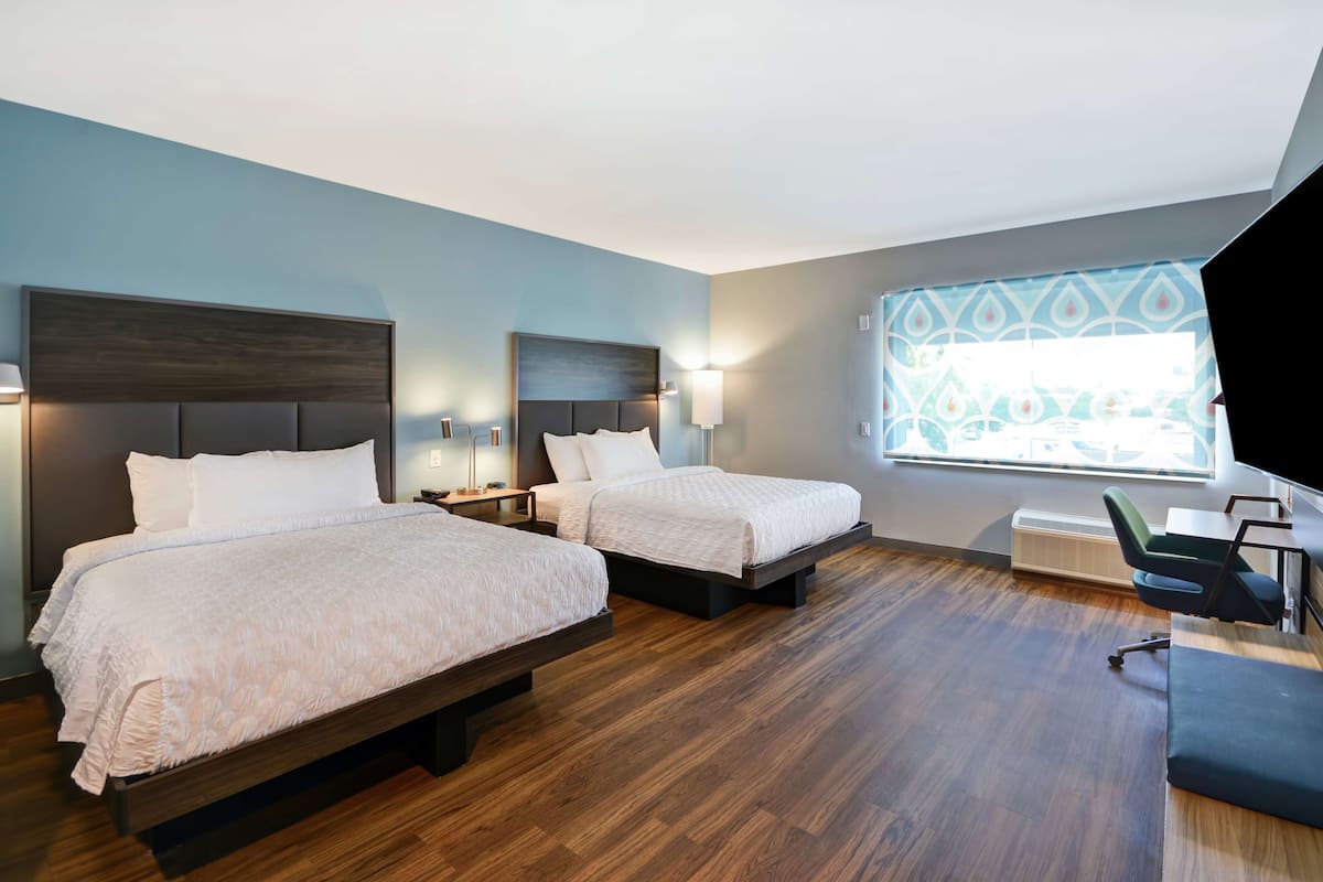 Une chambre d’hôtel avec deux lits, un bureau et une chaise.
