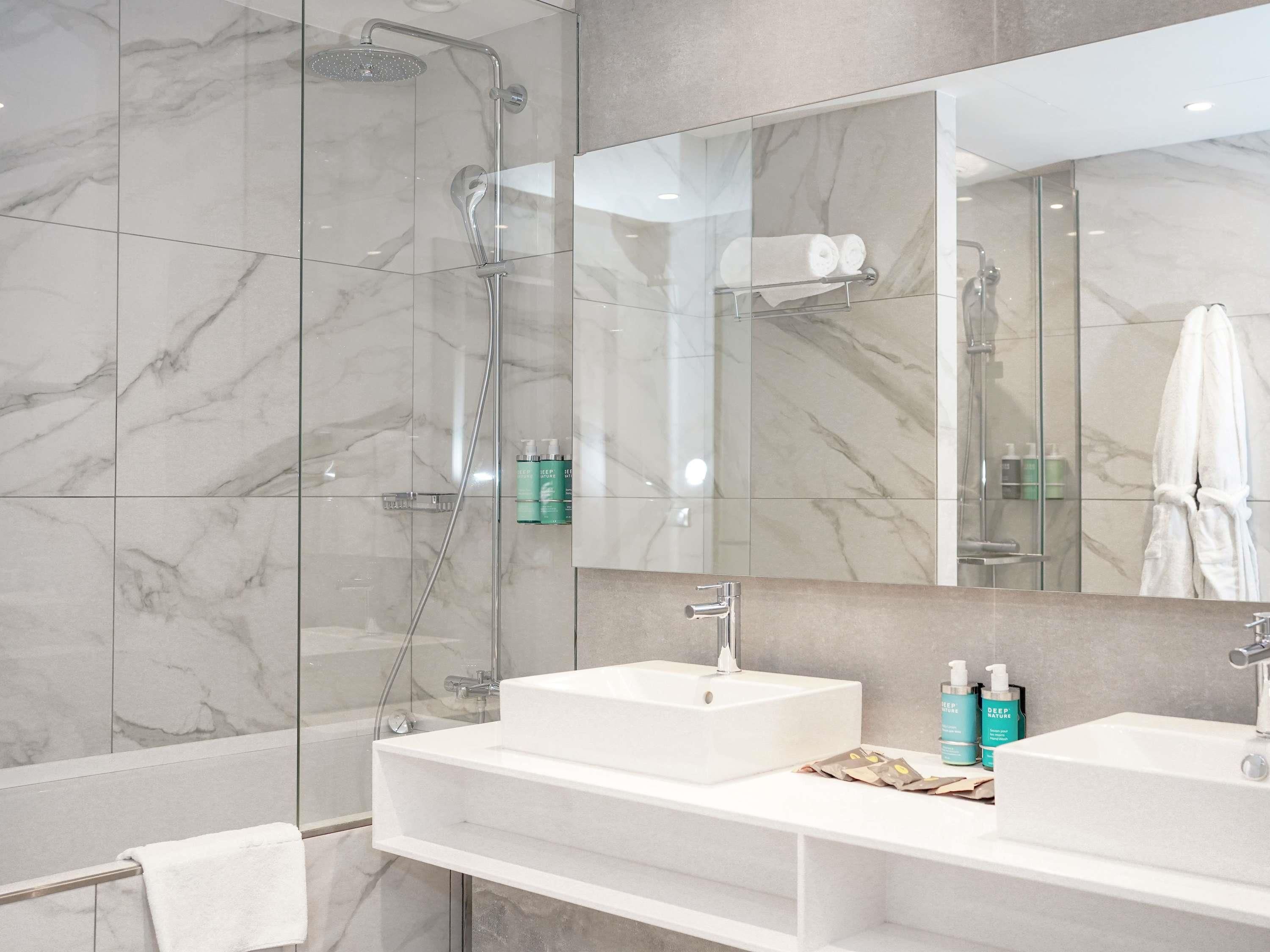 A modern bathroom with a glass-enclosed shower, two sinks, and a large mirror.