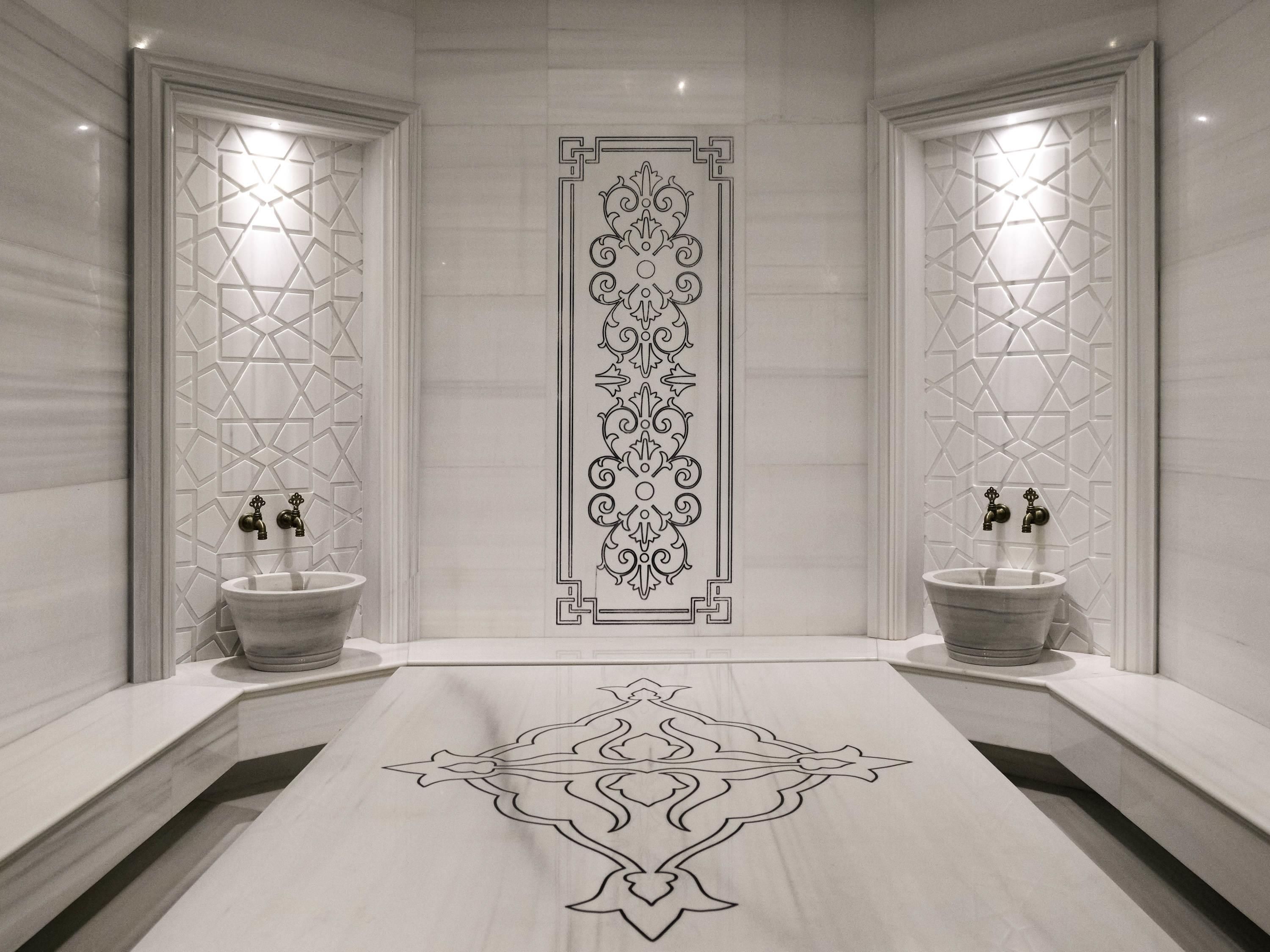 A modern bathroom with a central decorative panel, two sinks with faucets, and a marble floor.