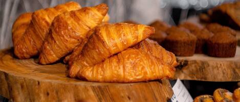 A display of pastries, including croissants and muffins, on wooden stands.