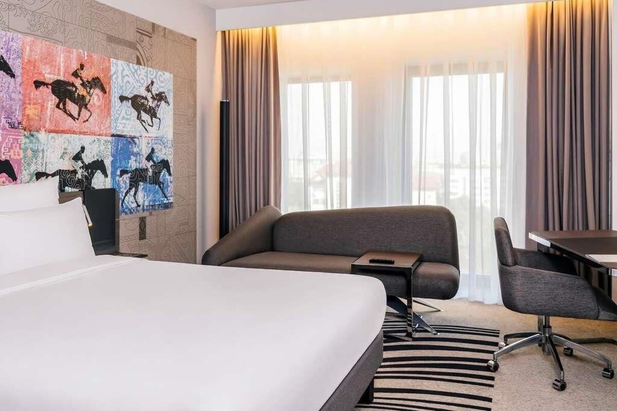 A hotel room with a bed, a sofa, a desk, and a chair.